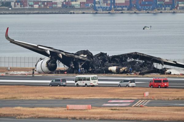 Officials look at the burnt wreckage of a Japan Airlines (JAL) passenger plane on the tarmac at Tokyo Internatio<em></em>nal Airport at Haneda in Tokyo.