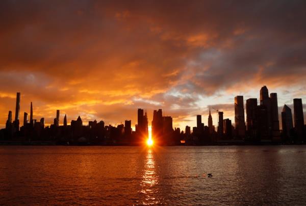 The sky turns orange as the sun rises above 42nd Street during a Manhattanhenge sunrise behind midtown Manhattan in New York City on November 28, 2022, as seen from Weehawken, New Jersey.