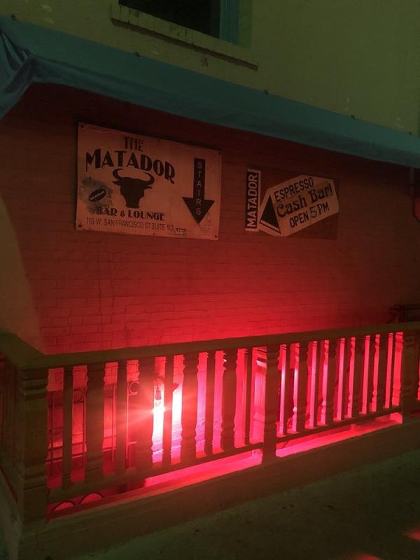 Exterior view of The Matador, an underground bar in Santa Fe, New Mexico, with a red light on a brick wall